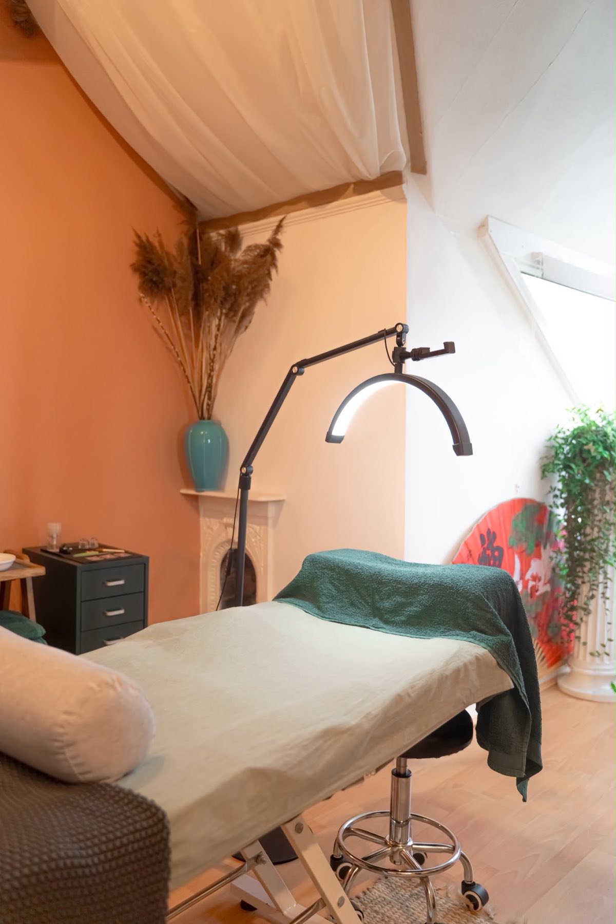 The treatment room — terracotta walls, fireplace mantel, dried pampas grass and warm afternoon light