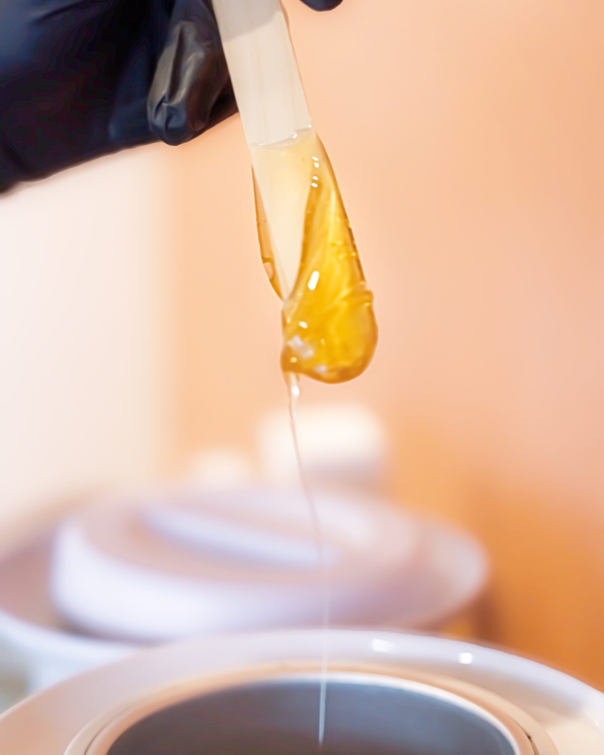 Warm wax dripping from a spatula over the wax pot